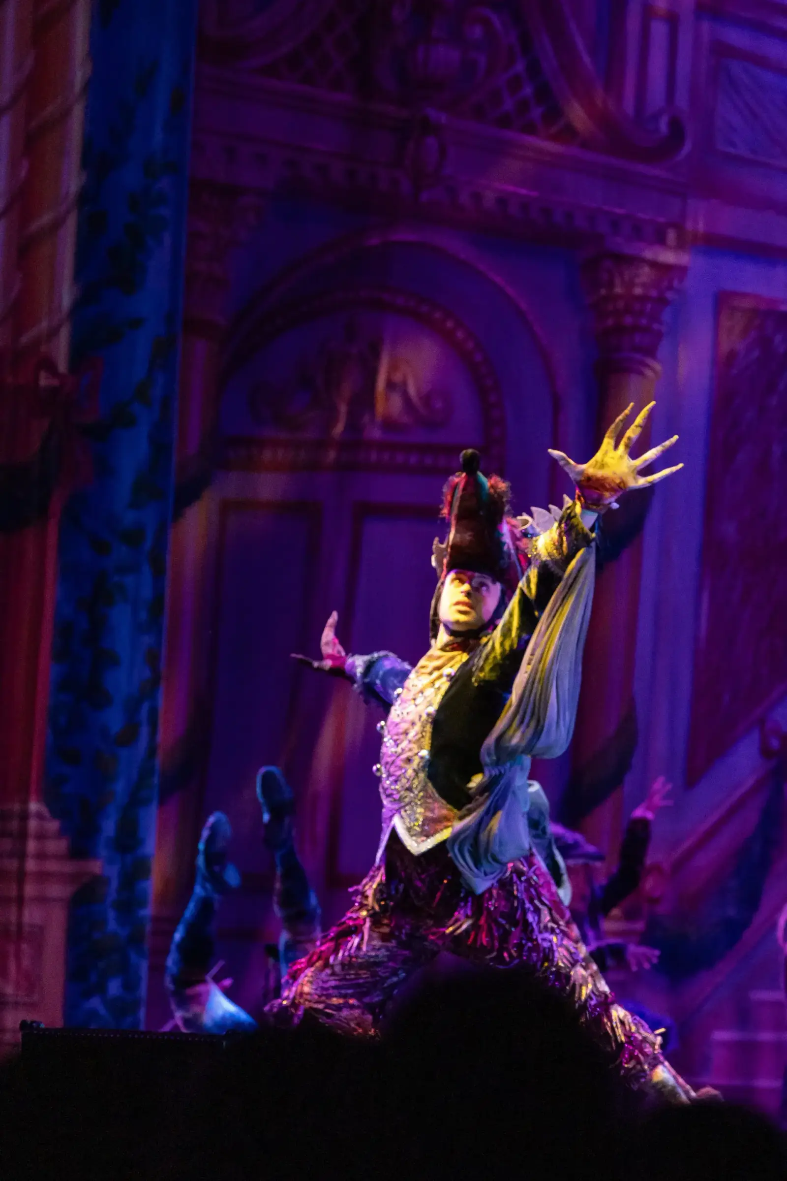 A performer in elaborate costume strikes a dramatic pose on a stage.