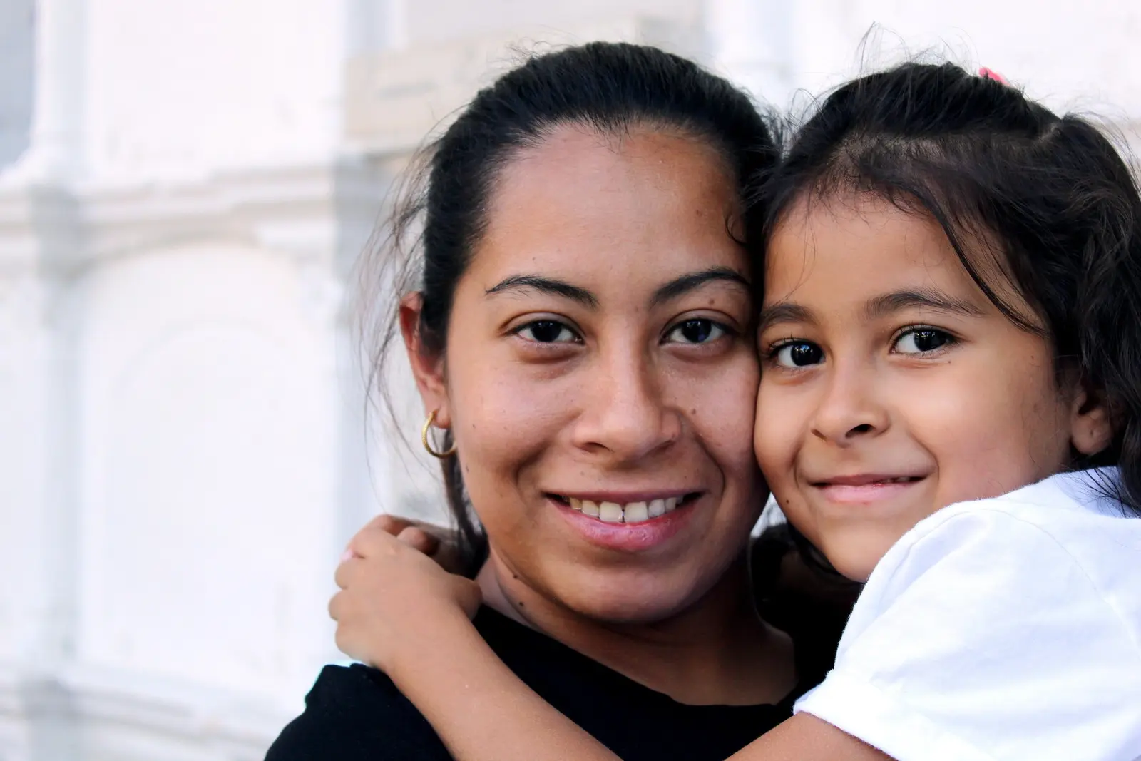 A mother and her daughter pose closely together for a portrait.