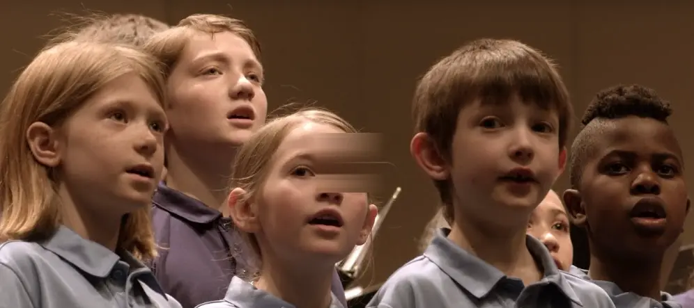 A group of children sing together in a choir.