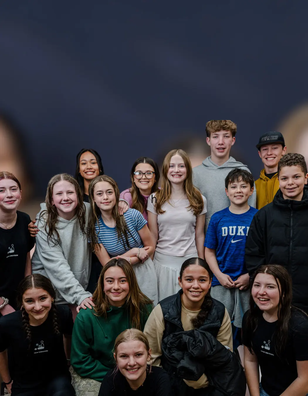 A group of teenagers poses for a photo against a plain background.