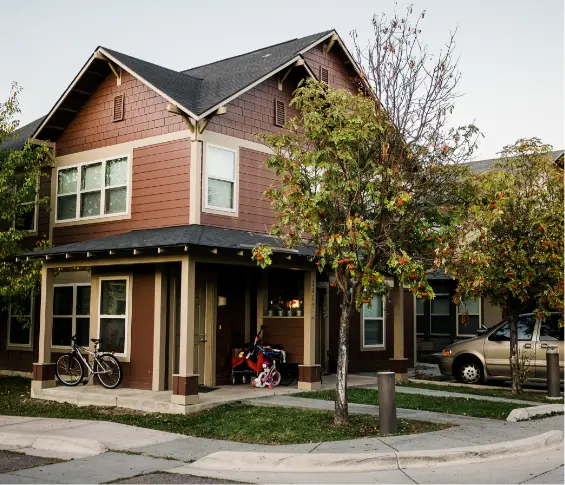 A residential building with a front porch, a bicycle, and a small child's toy near the entrance.