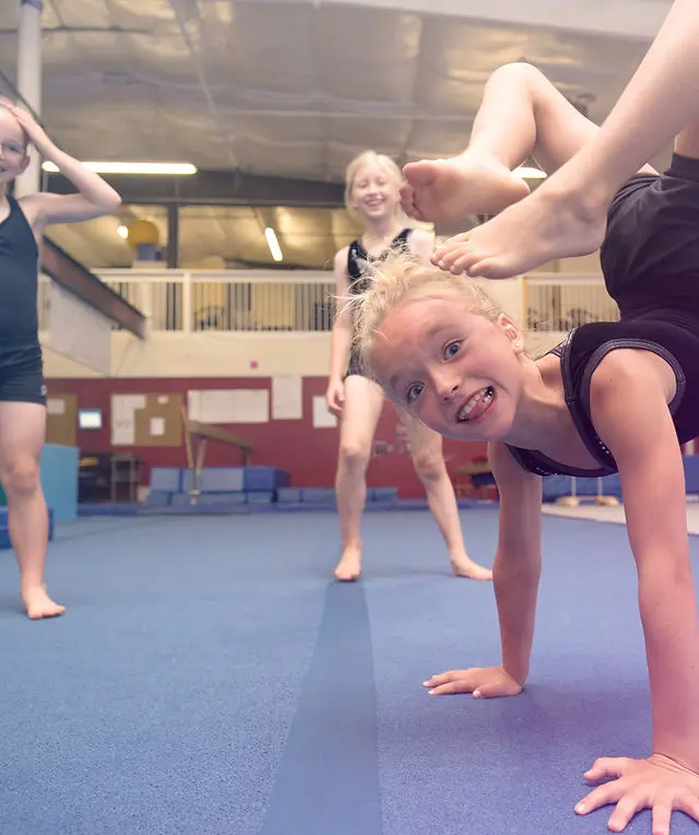 Young girls practice gymnastics in a training facility.