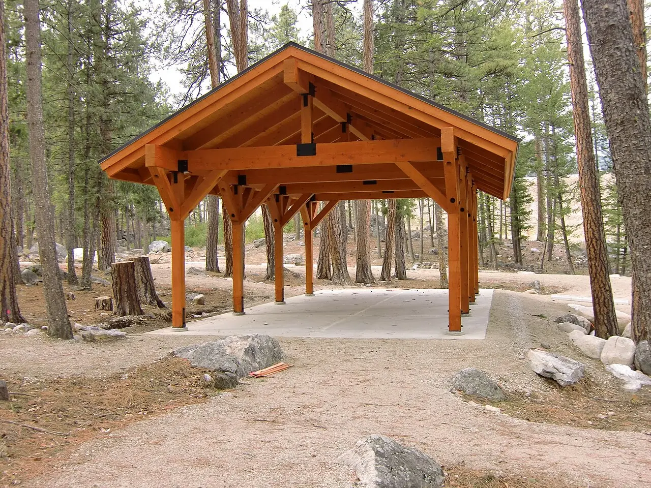 A wooden pavilion structure stands in a forest clearing.