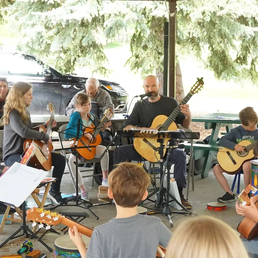 Group guitar lesson in a park pavilion.