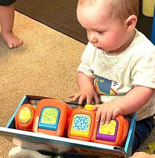 A toddler plays with a toy in a box.