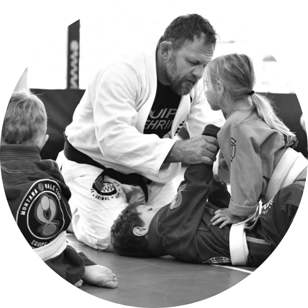 An instructor supervises children in a martial arts class.
