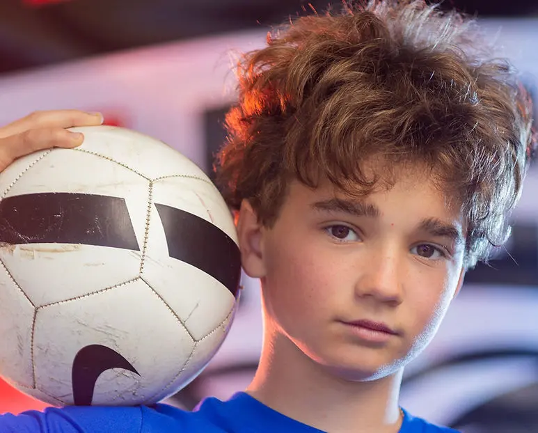 A young boy poses with a soccer ball.
