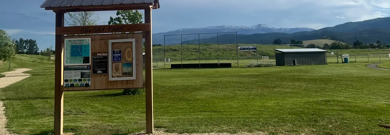 Signs at Big Sky Park with the baseball field in the background