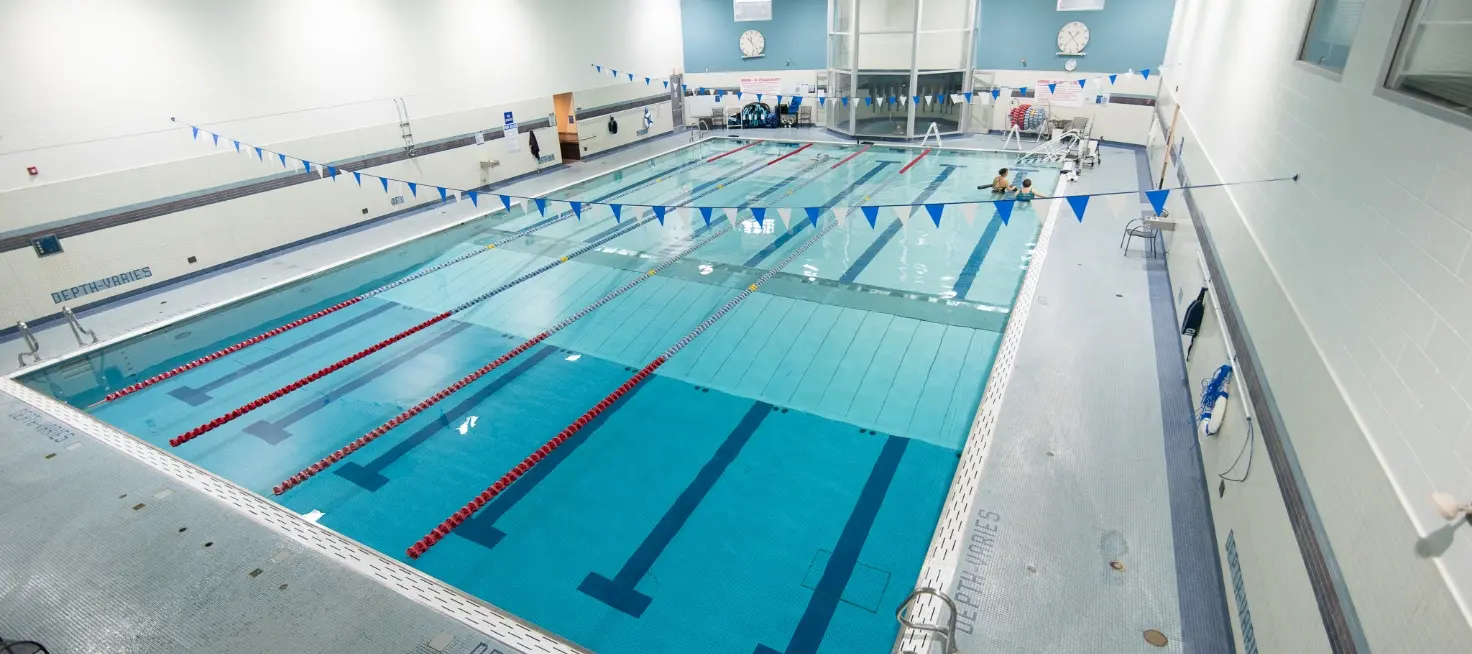 An indoor swimming pool with lap lanes and a few people in the water.