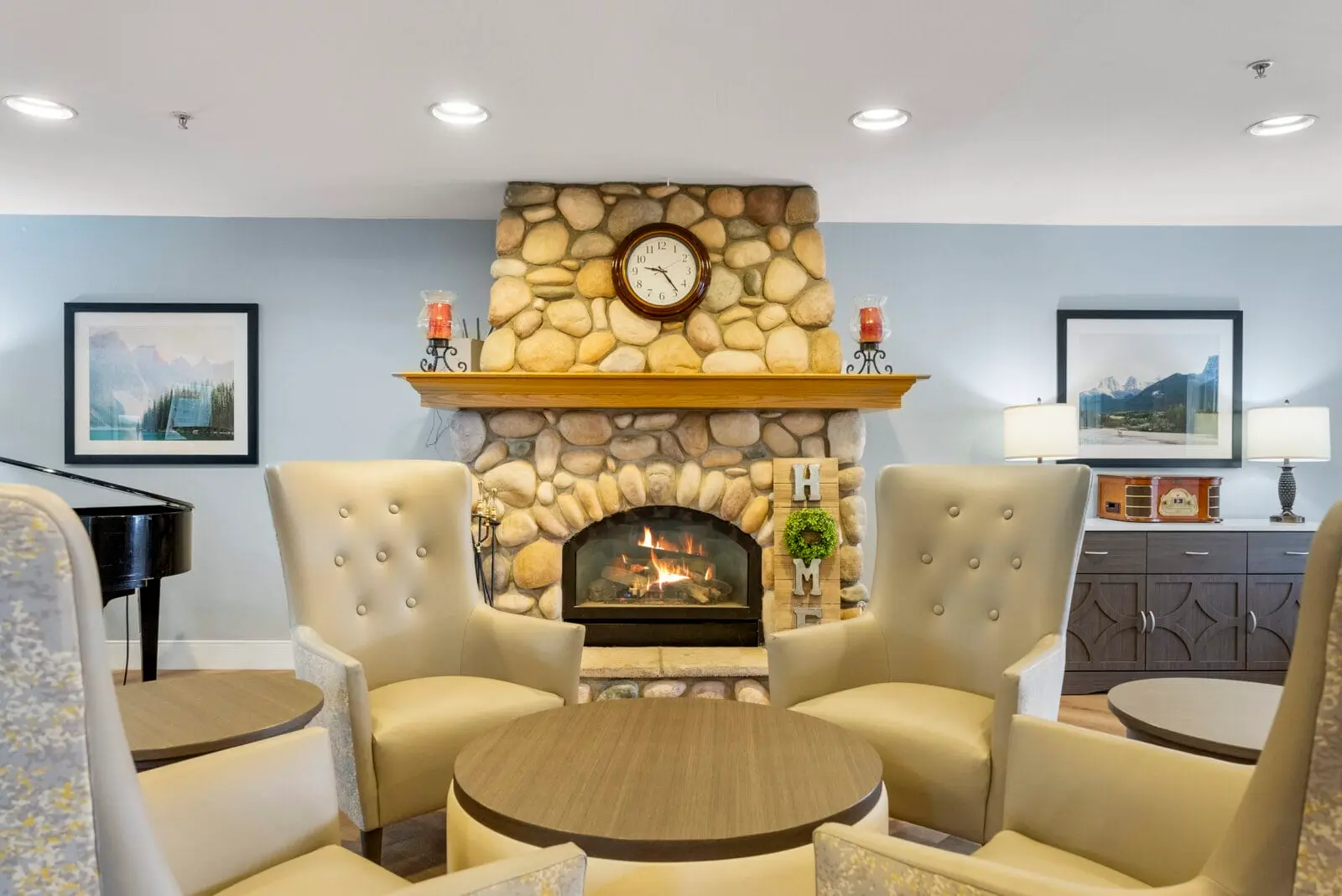 A cozy lounge area centers around a stone fireplace and a round table with upholstered armchairs.