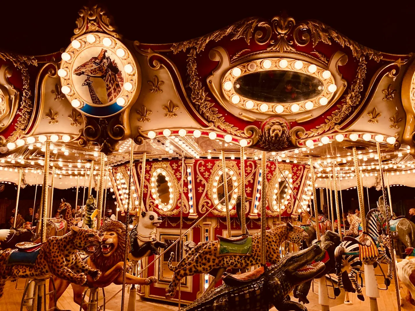 A brightly lit carousel features various animal figures such as a leopard, lion, panda, crocodile, and zebra.