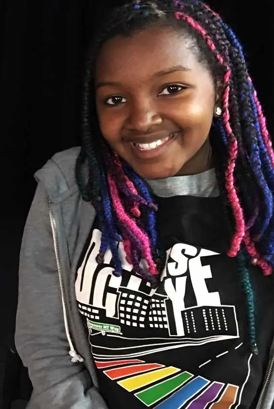 A girl with colorful braids smiling.
