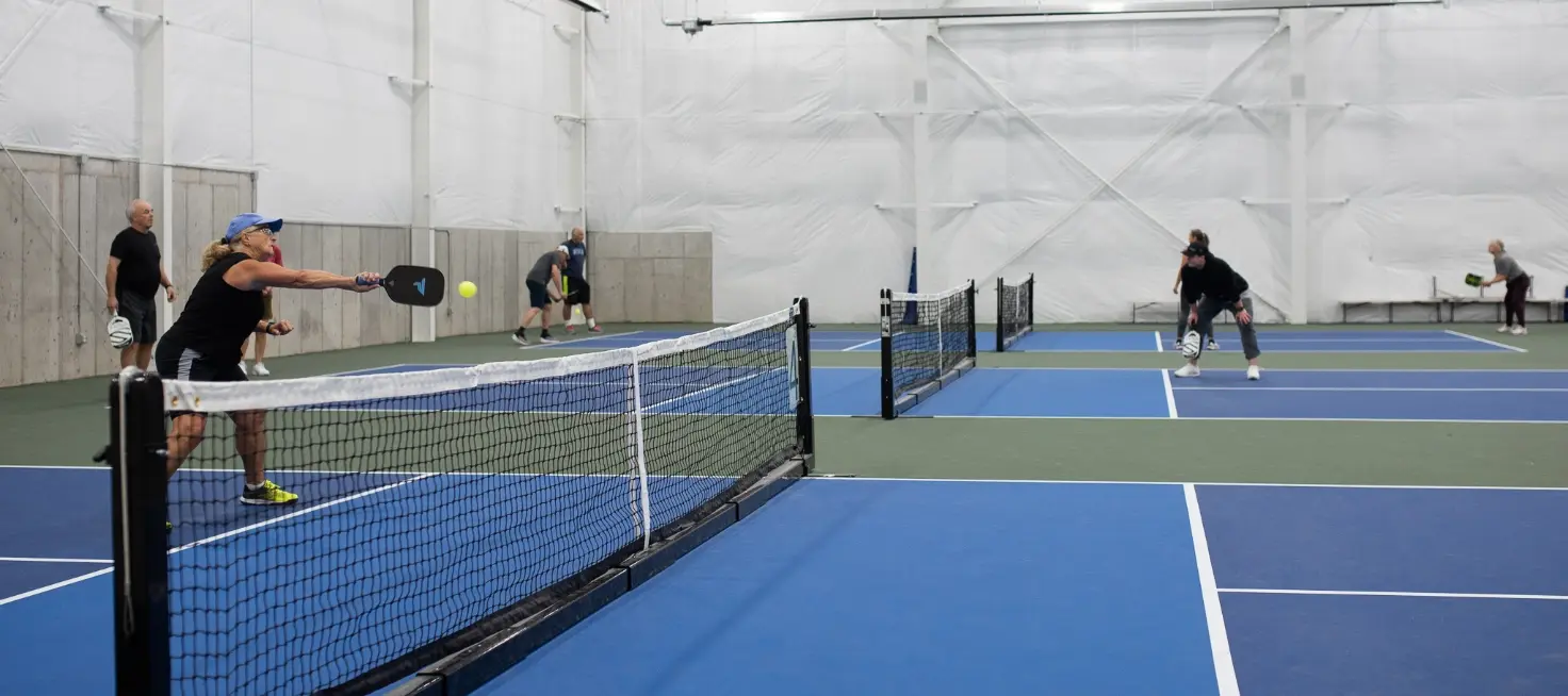 People are playing pickleball on indoor courts.