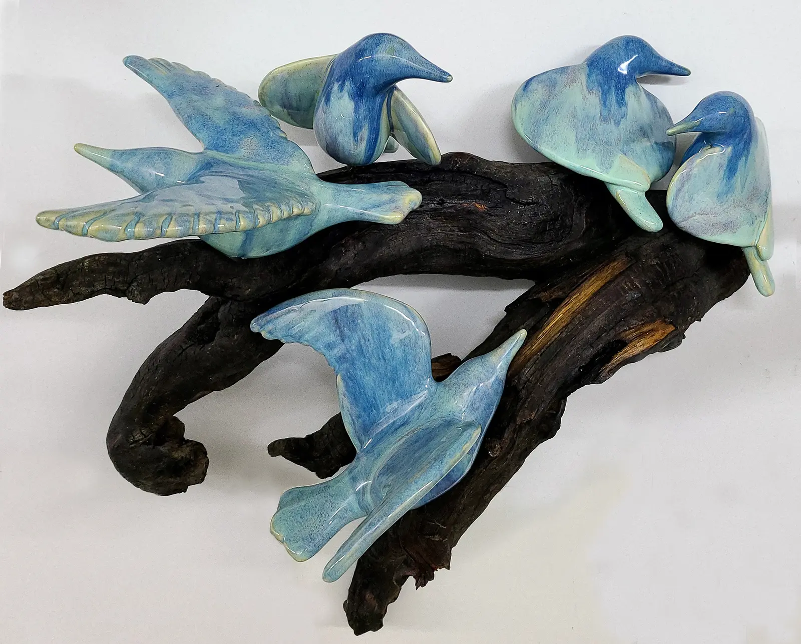 Several blue ceramic birds are mounted on a piece of dark driftwood.