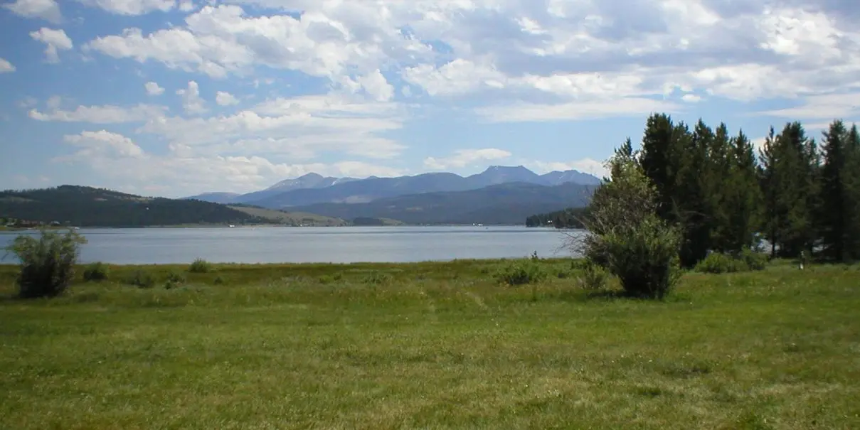 A scenic view of a lake with mountains in the background under a blue sky.