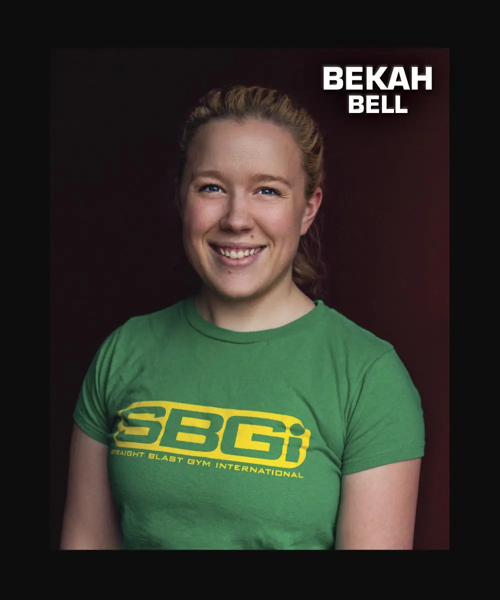 A smiling woman wears a green t-shirt with a company logo.