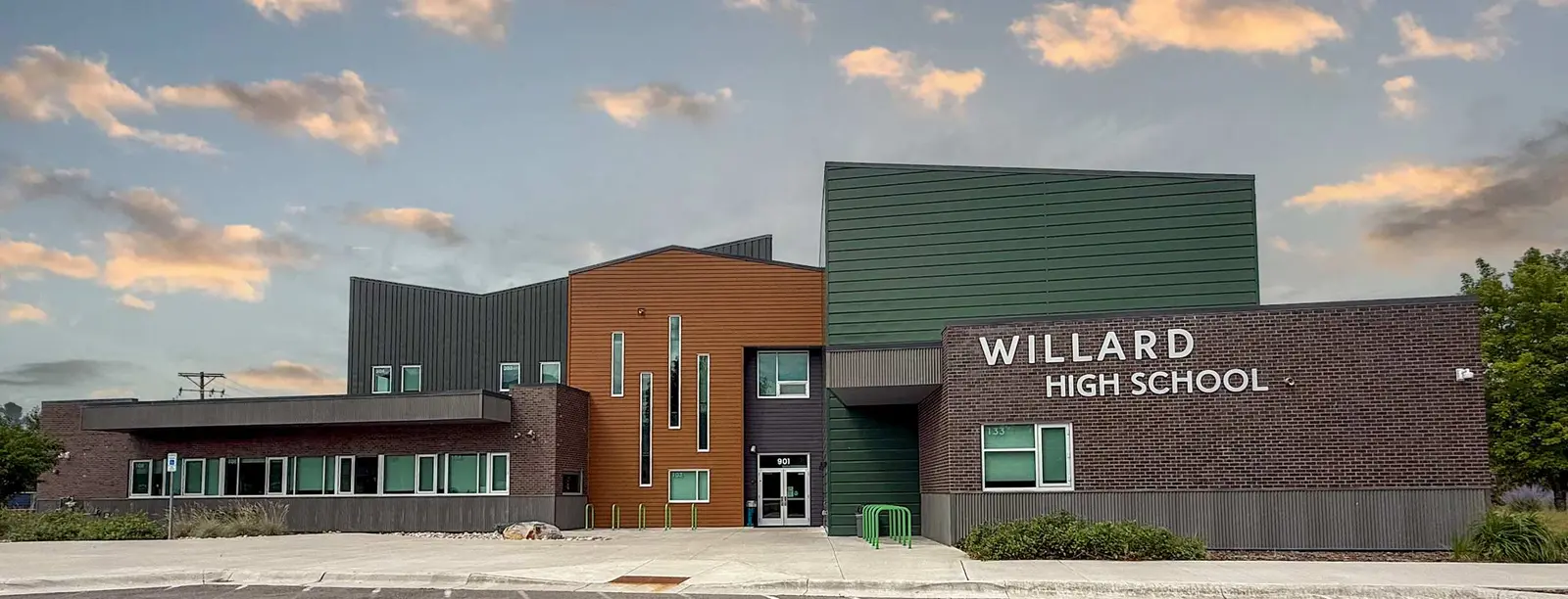 A modern school building exterior under a cloudy sky.
