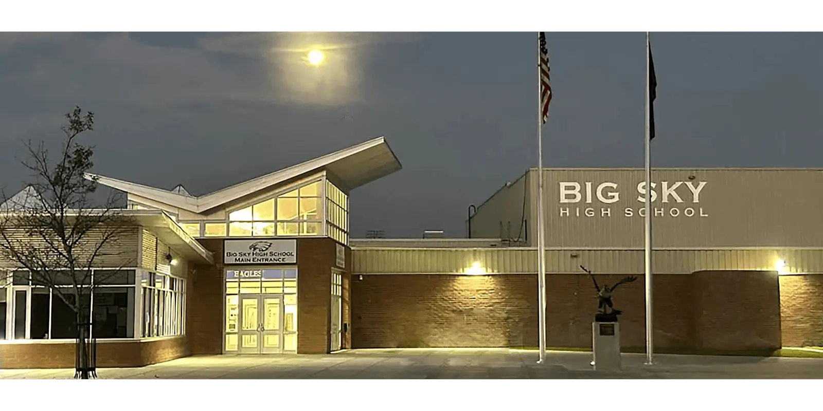 front of big sky high school with flags and eagle statue