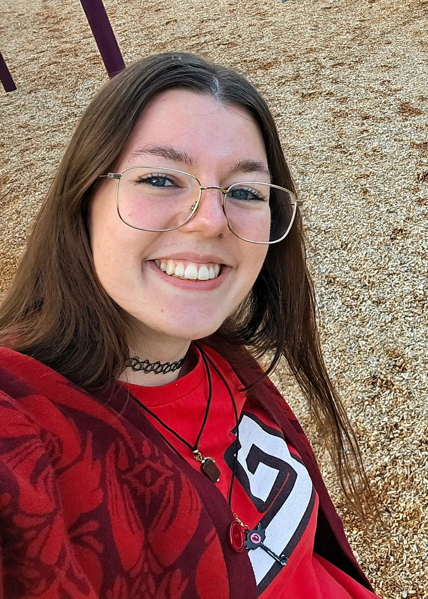 A smiling young woman poses for a selfie outdoors.