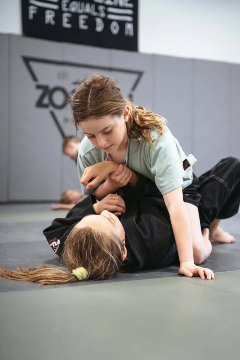 Two children practice martial arts together on a mat.
