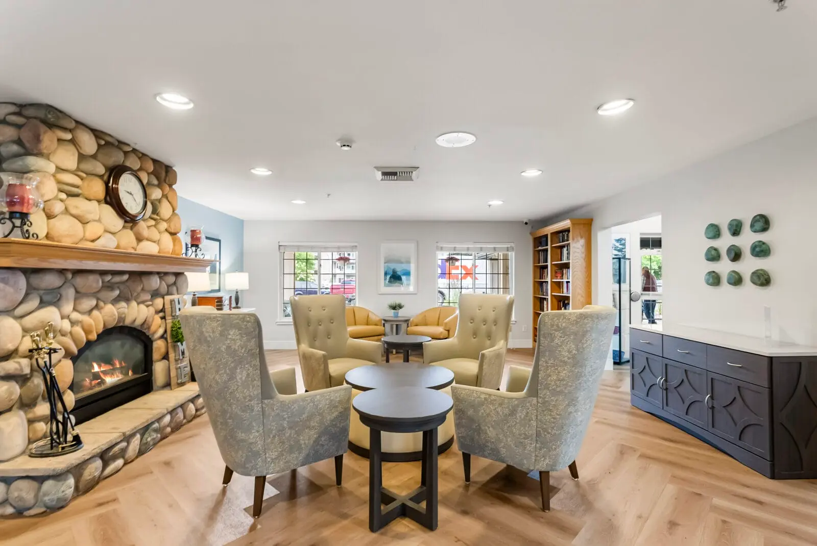 A cozy lounge area features a stone fireplace and several comfortable armchairs arranged around small tables.