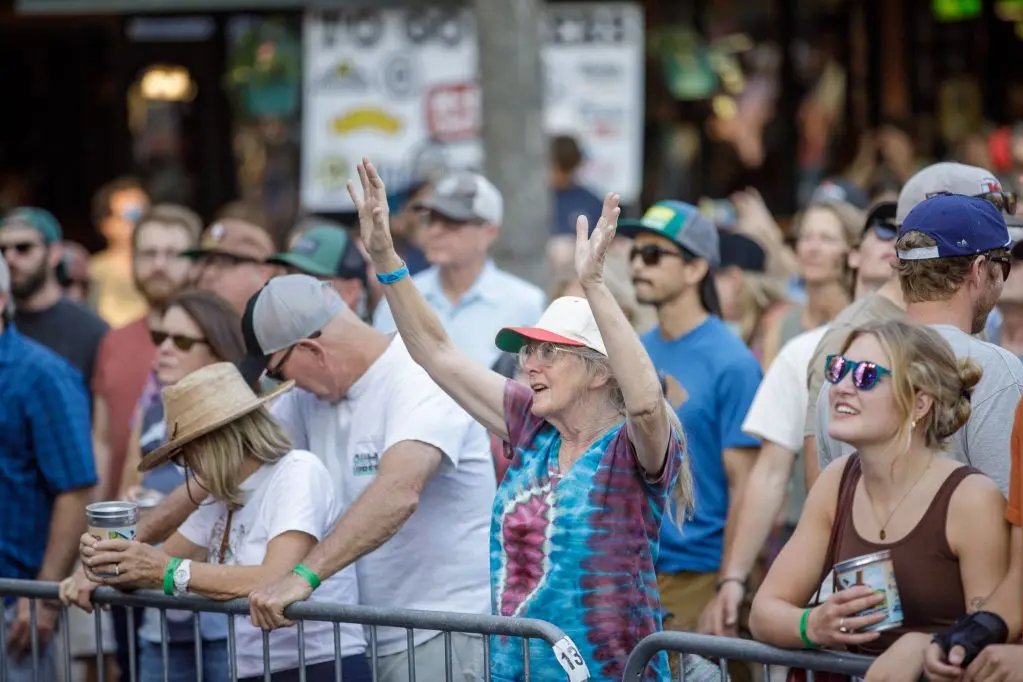 A group of adults stands behind a metal barricade at an outdoor event.