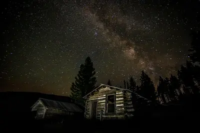 Photo from flickr.com A rustic log cabin sits under a starry night sky with the Milky Way visible.