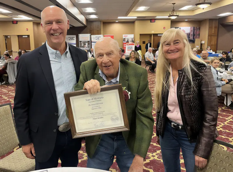 Helena centenarian Richard Blossom, middle, receives a framed certificate from Governor Greg Gianforte and First Lady Susan Gianforte during the 2025 Centenarian luncheon.