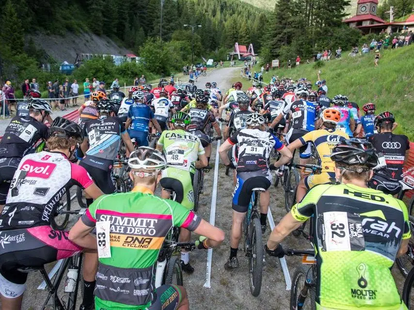 A large group of cyclists wait at the starting line for a mountain bike race.