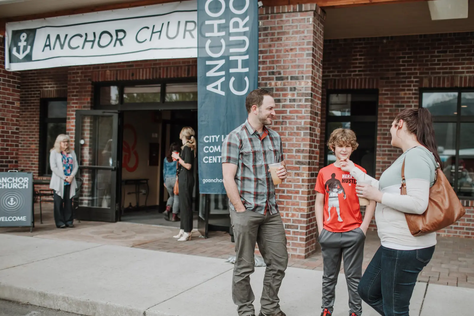 A group of people gathers outside a church entrance.