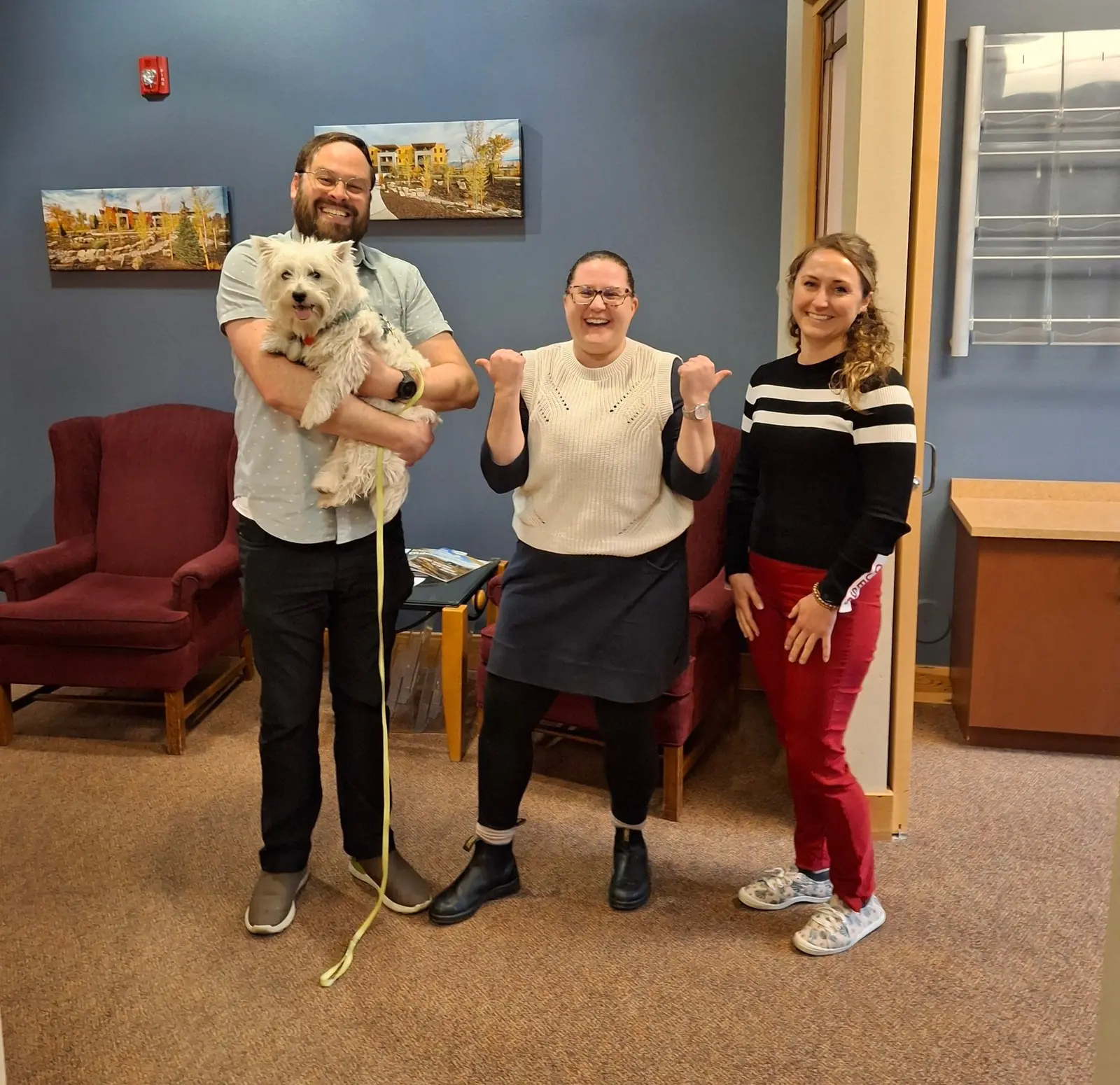 Homebuyer Educator Alex holding office dog Maggie, Program and Operations Director Julie and Financial Educator Chelsea together in the Homeword office