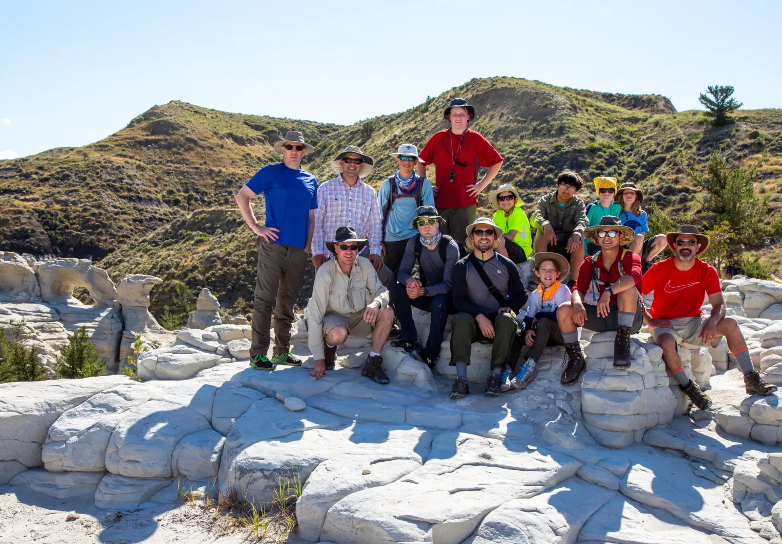 A large group of children and adults pose together on a rugged rocky landscape during an outdoor excursion.