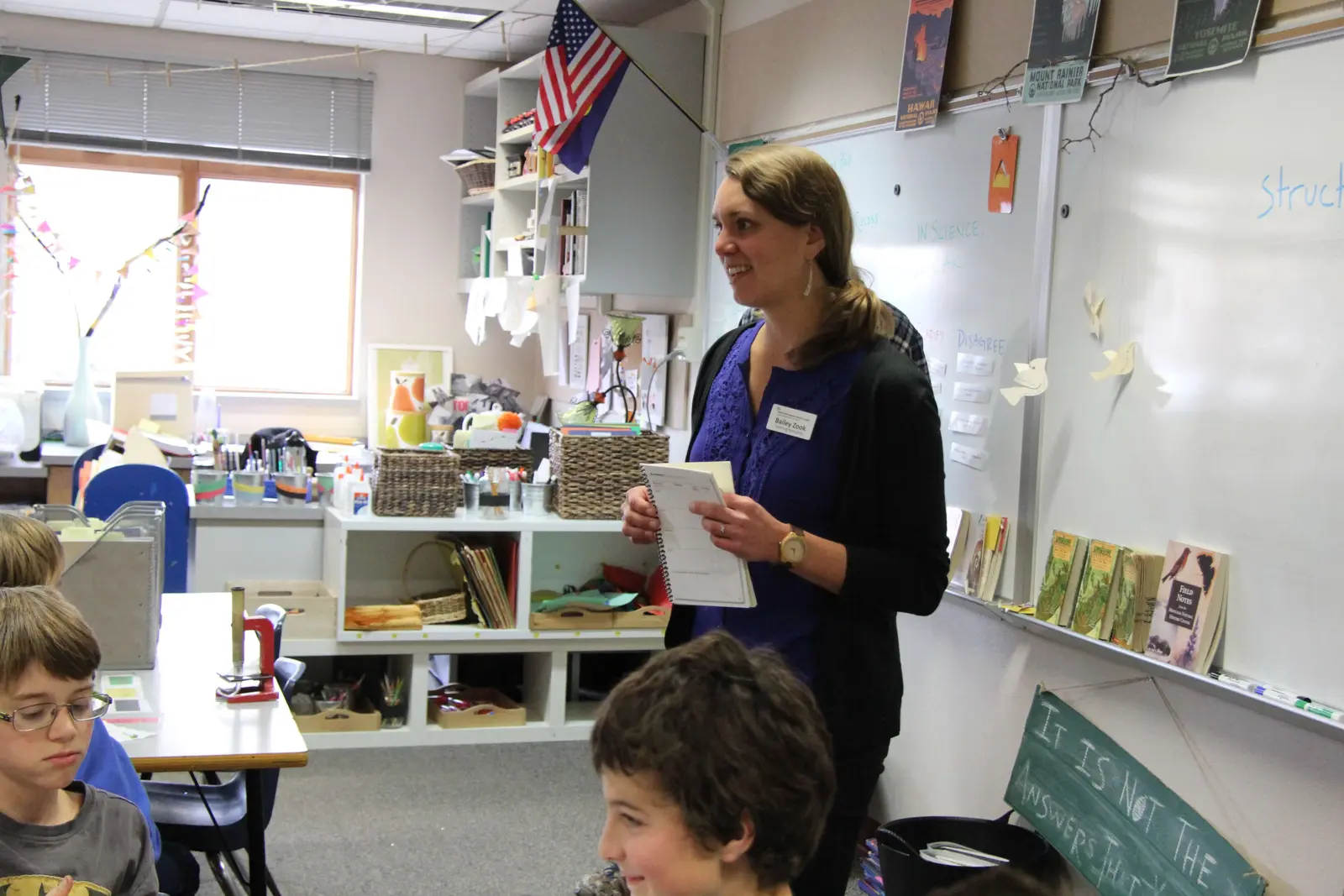 An instructor stands in a classroom while speaking to students.