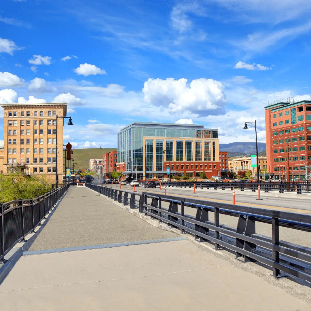 A view across a bridge looking toward city buildings under a partly cloudy sky.