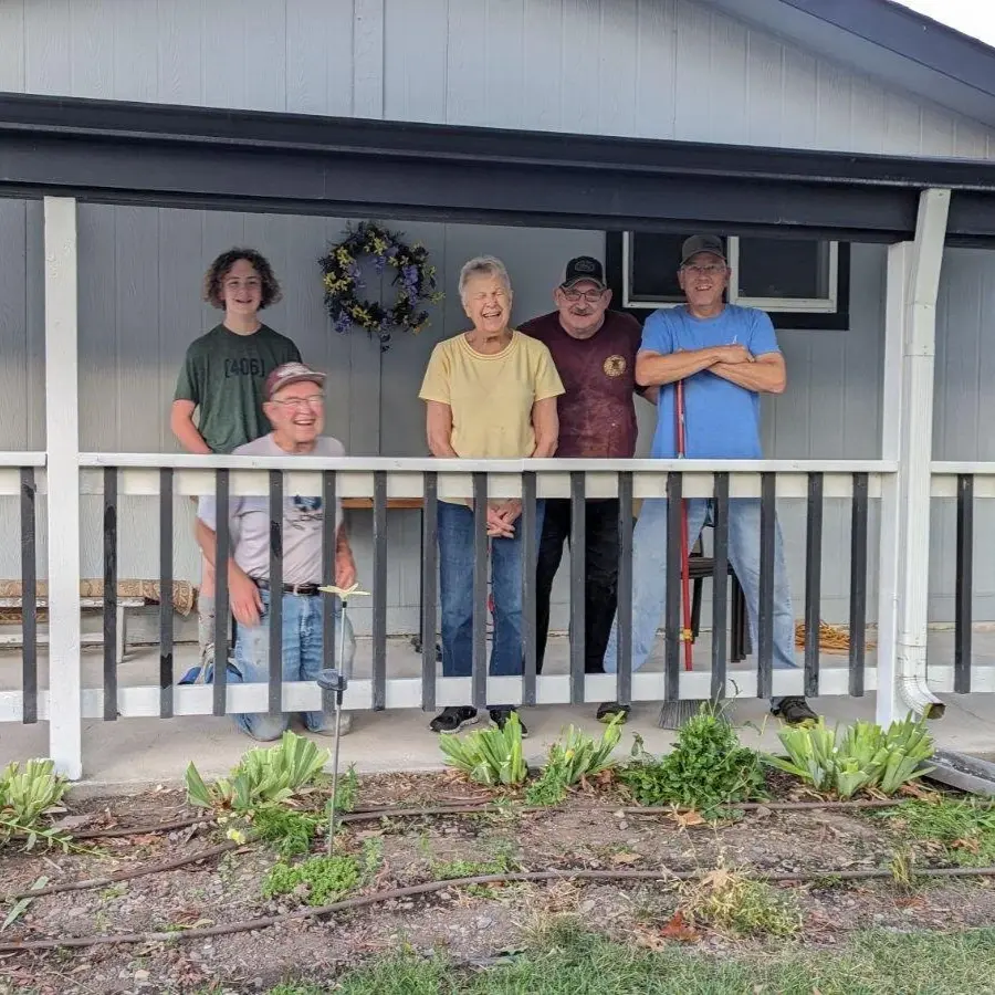 A group of people standing and kneeling together on a porch.