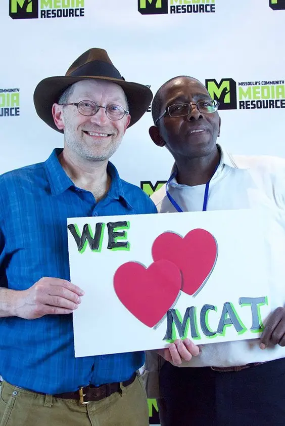 Two men holding up a sign that says we love MCAT.