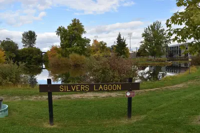 Photo from livingnewdeal.org A sign labeled 'Silvers Lagoon' stands before a tranquil pond.