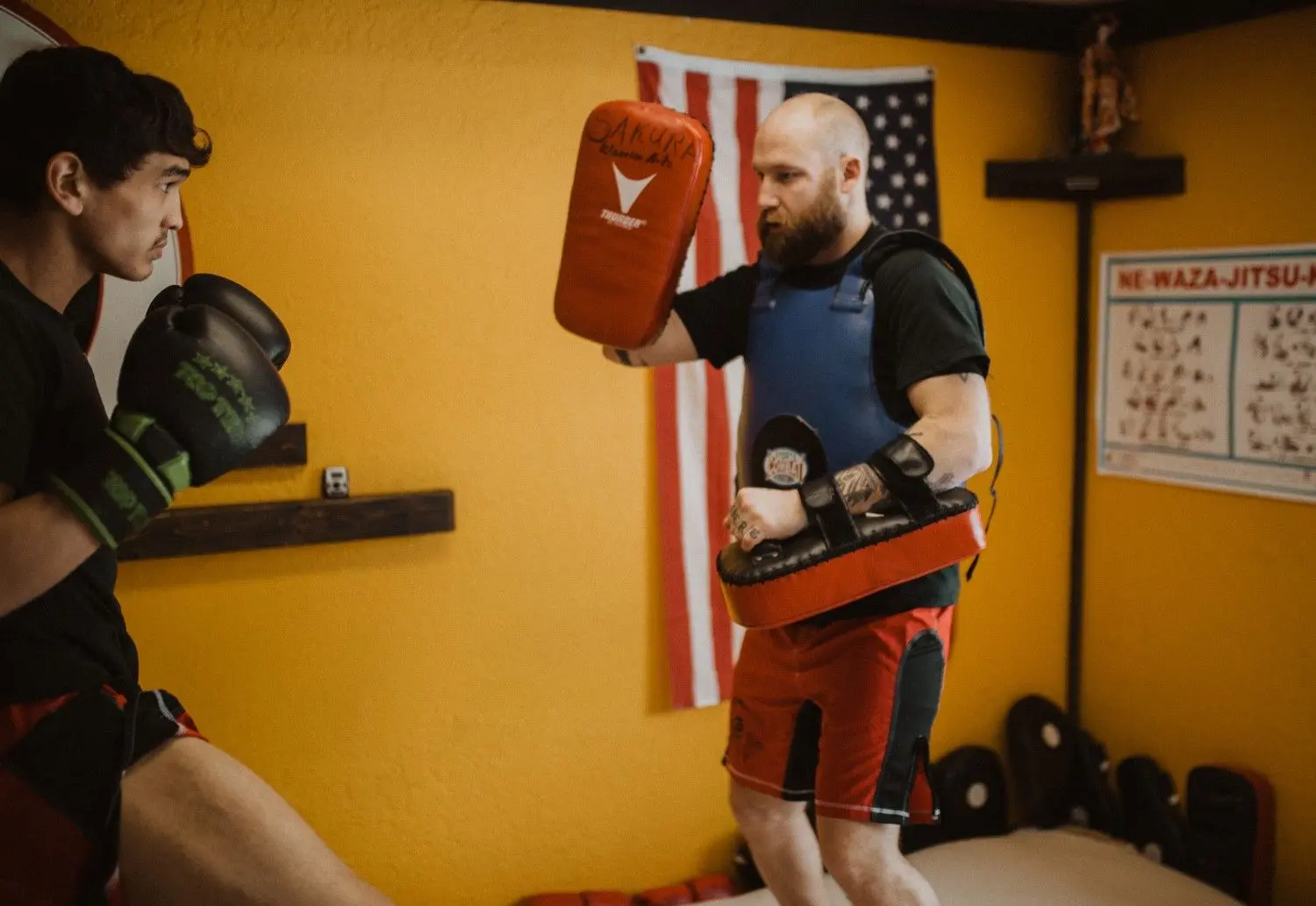 A martial arts instructor holds training pads for a student to practice kicking.