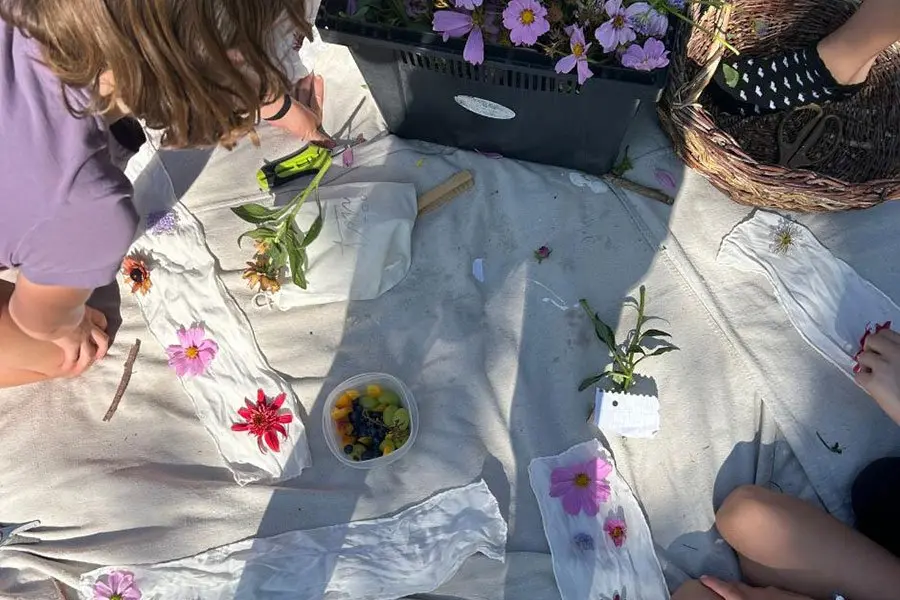 People arrange flowers on white fabric while participating in an outdoor activity.