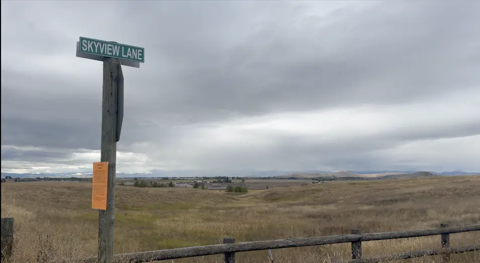 A street sign for Skyview Lane stands in an open landscape under a cloudy sky.