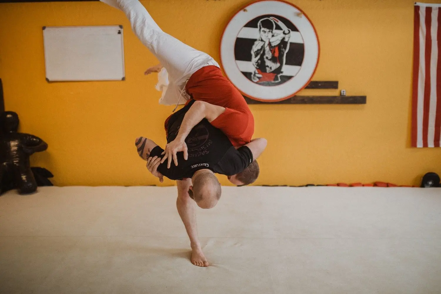 Two men practice a martial arts move in a studio.
