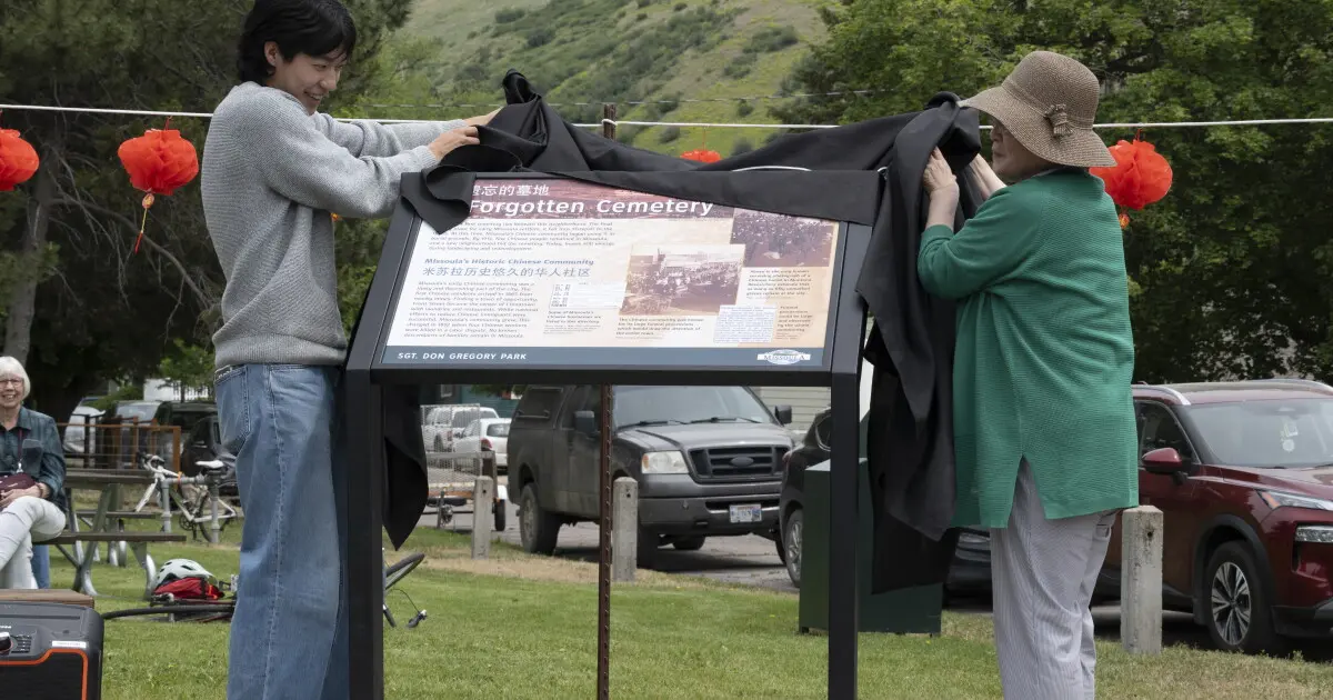 Kim and his grandmother, who made the trip from Seoul, South Korea, lift the cover from the newly installed plaque in Missoula’s Gregory Park on June 6.