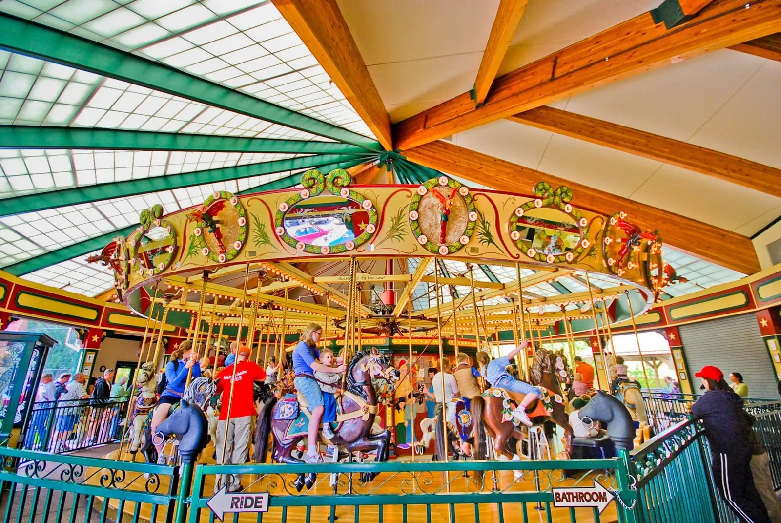 People enjoy riding a carousel inside a large covered structure.
