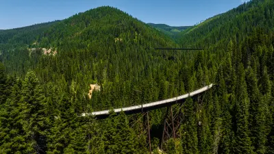 Shuttle schedule sign over a lush green forest with a mountain backdrop.