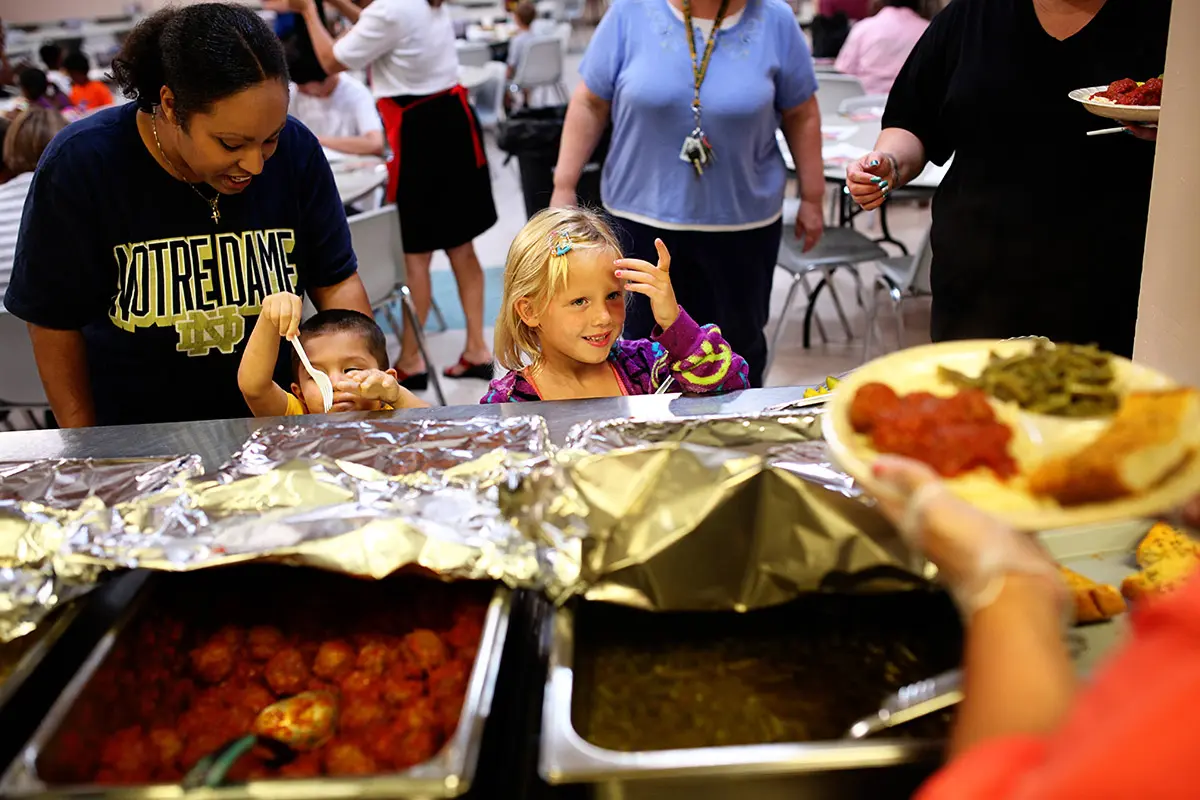 A woman and two children look at food served at a buffet line.
