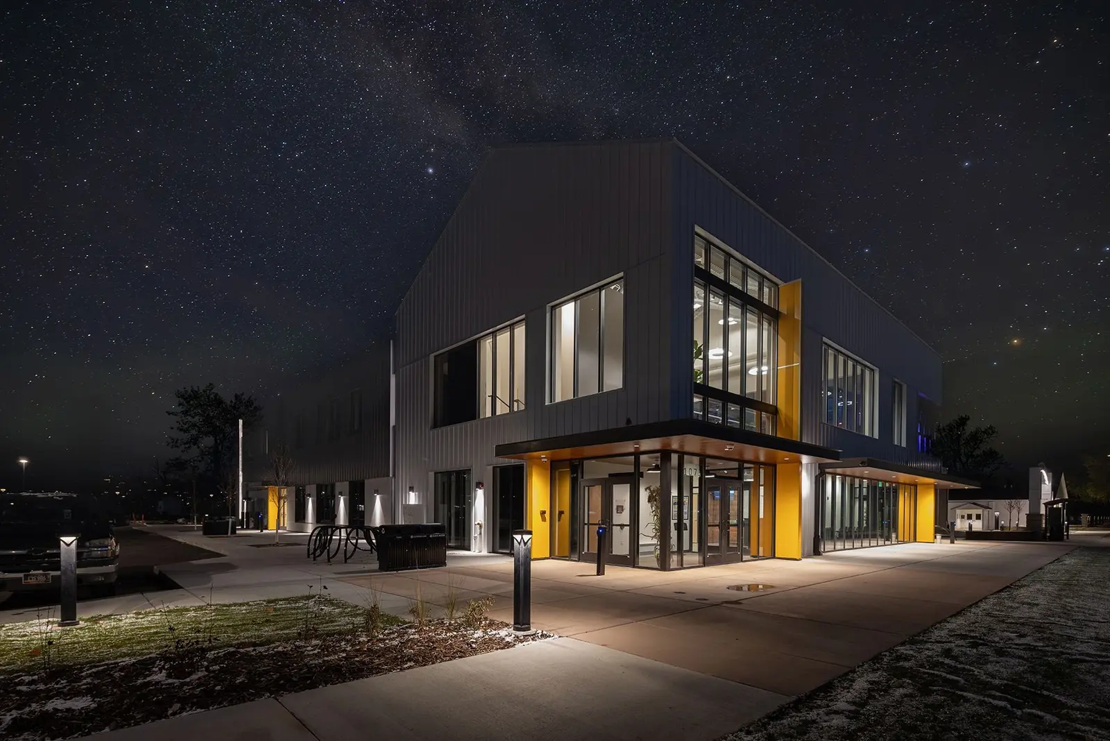 A modern building with yellow accents stands under a star-filled night sky.