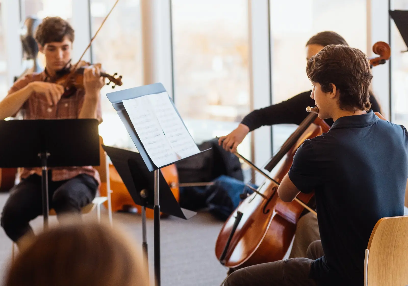 Young musicians are playing string instruments during a practice session.