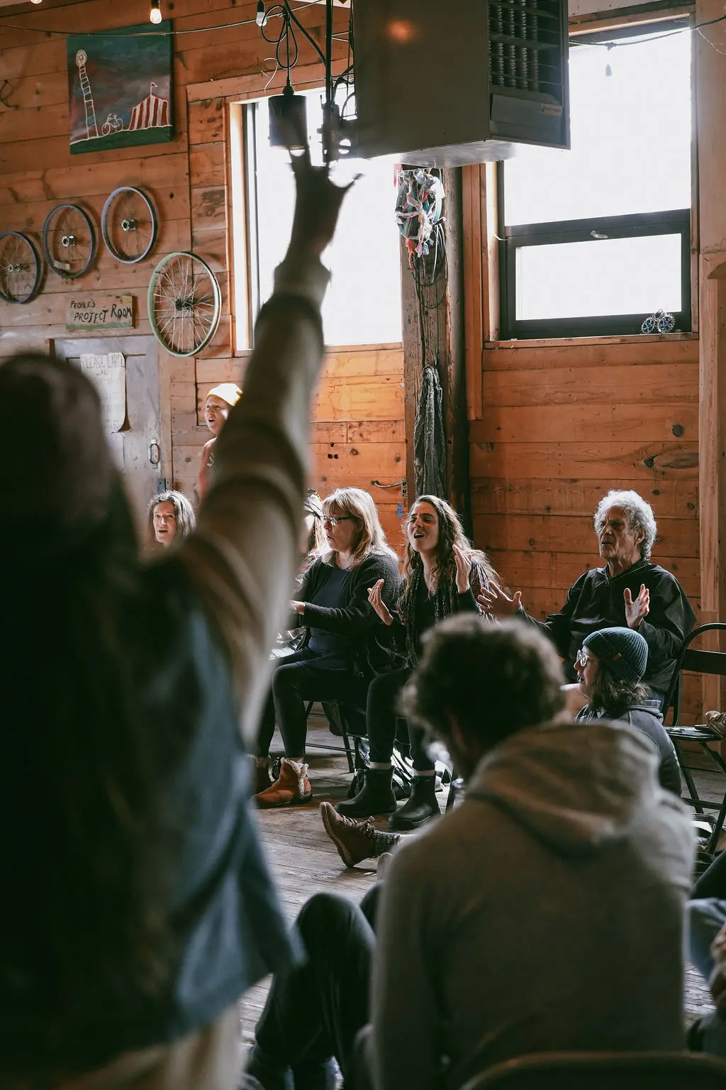 A group of adults participate in a workshop in a room with wood-paneled walls.