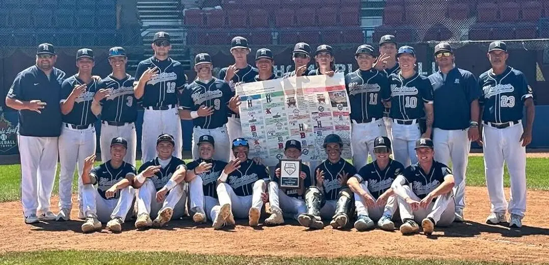 A baseball team poses together for a group photo on a field while holding a tournament bracket and a trophy.
