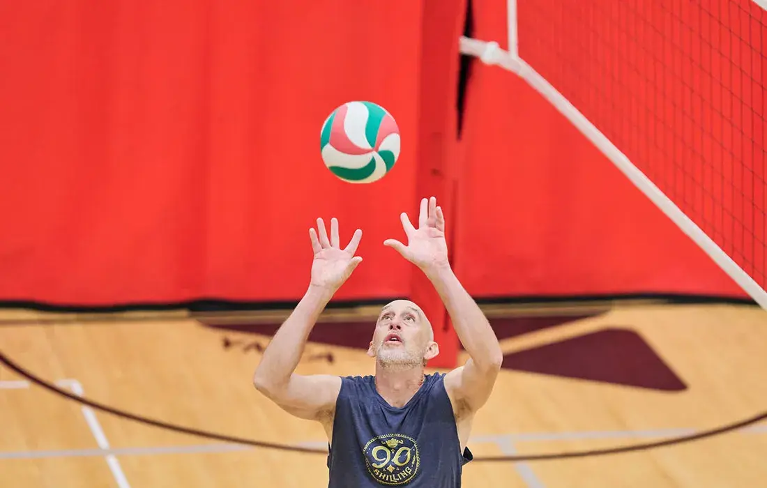 A man plays volleyball indoors.